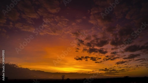 Stunning sunrise timelapse over African plains with mountains and red sky, clouds illuminated photo