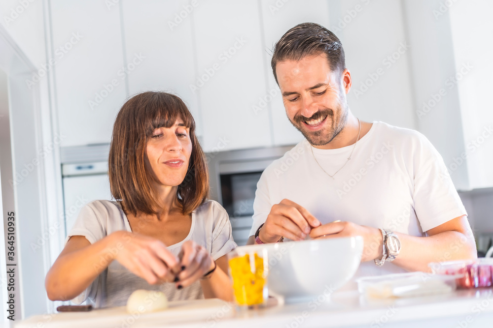 A Caucasian couple cooking together at home, cooking in confinement, cooking with the family. Coronavirus, covid-19. Cooking two lovers