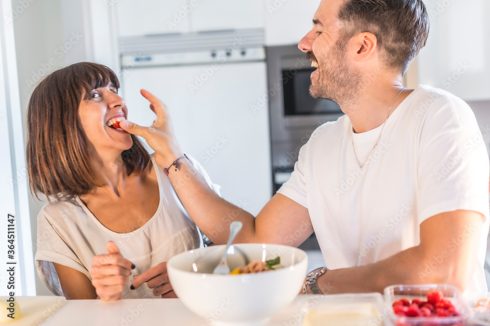 A Caucasian couple cooking together at home, cooking in confinement, cooking with the family. Coronavirus, covid-19. Boyfriend giving a blackberry in romantic way to the girlfriend A Caucasian couple cooking together at home, cooking in confinement, cooking with the family. Coronavirus, covid-19. Boyfriend giving a blackberry in romantic way to the girlfriend