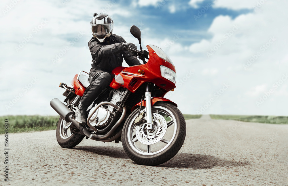 A man rides a motorcycle on the highway to the camera. A man on a red motorcycle makes a turn in front of the camera