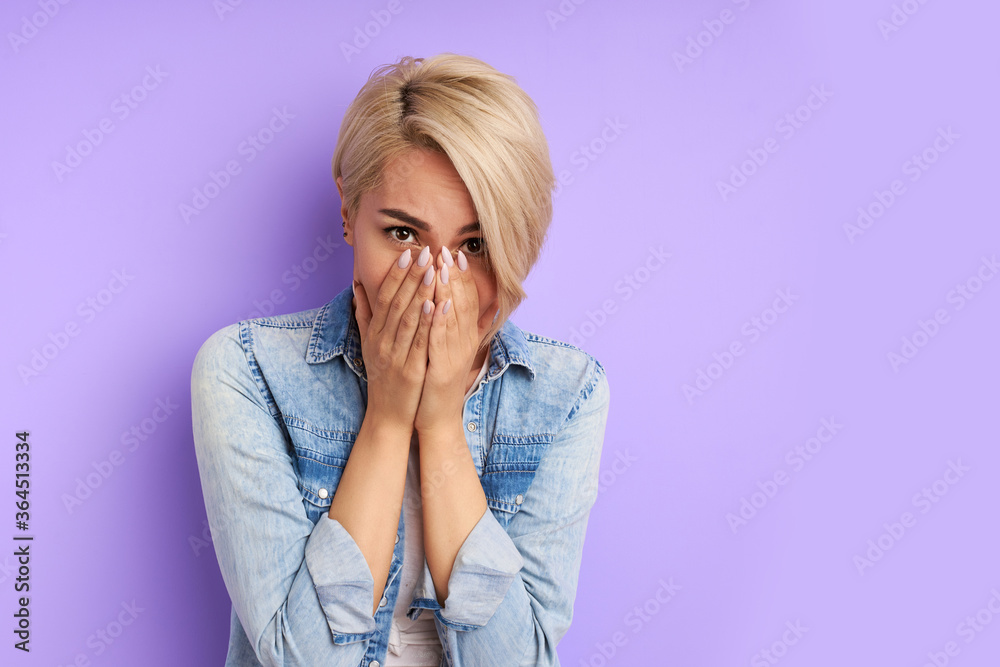 confused young caucasian woman in shock, close her mouth and look at camera isolated over purple background confused young caucasian woman in shock, close her mouth and look at camera isolated over purple background