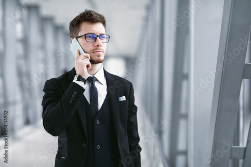 Serious business man talking on smartphone wearing specs