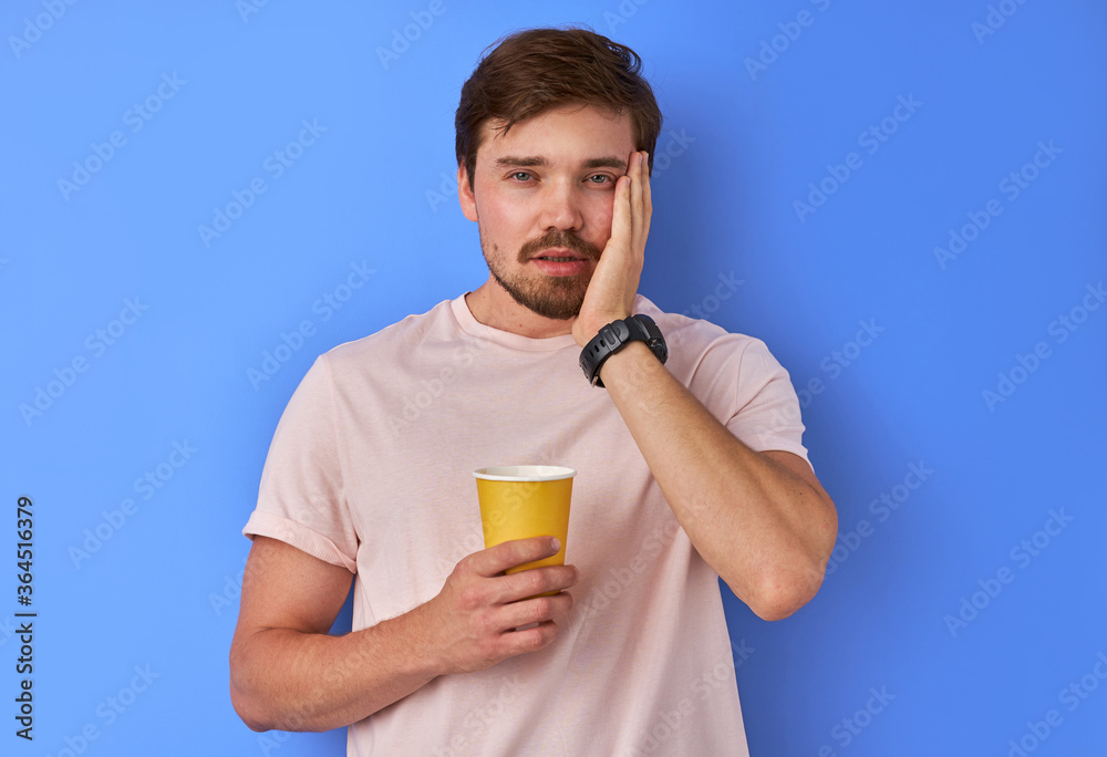 sleepy man holds a cup of tea in hands and looks at camera, after waking up, in the morning sleepy man holds a cup of tea in hands and looks at camera, after waking up, in the morning