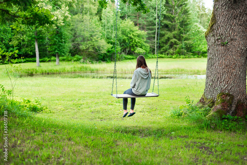 girl swinging on a swing by the lake in the forest