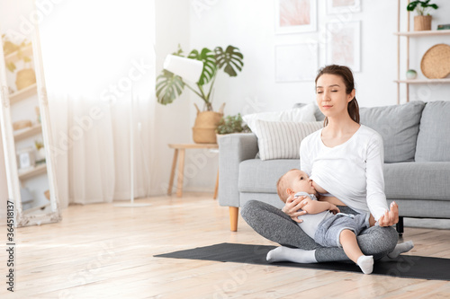 Relaxed Young Mother Meditating While Breastfeeding Her Baby At Home, Practicing Yoga