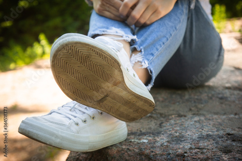 Female feet in jeans and sports shoes.