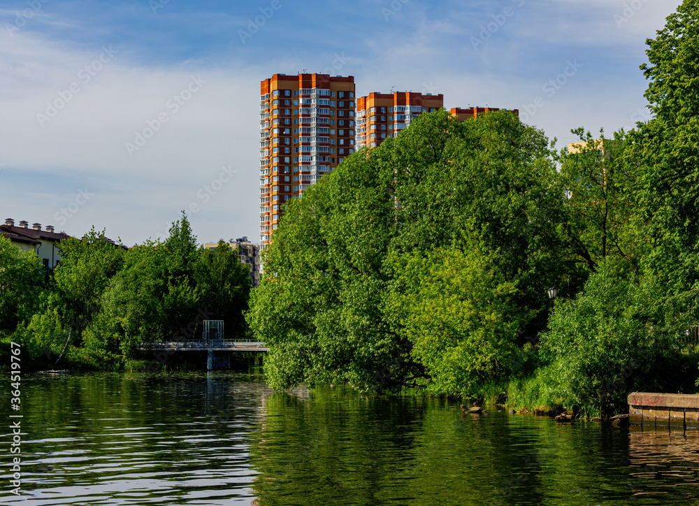 Landscape with a residential complex on the river Bank with a blue sky.