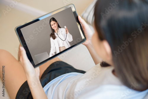 Tablet monitor view over girl shoulder, A doctor woman is wearing uniform and give consultation to young women about Coronavirus prevention, Health care technology concept