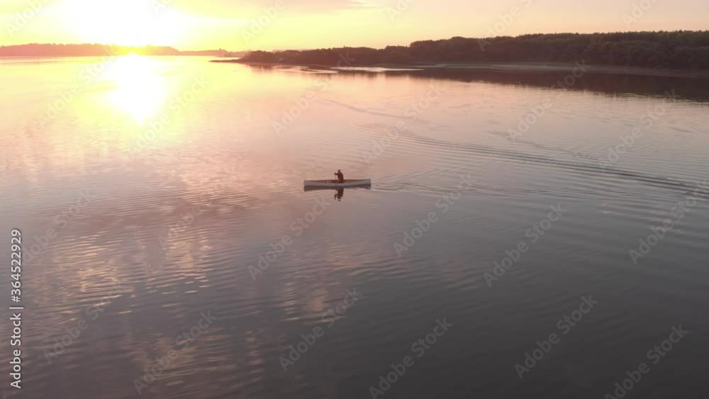 AERIAL Mid 50s Caucasian male canoeing on a traditional wooden boat on a large lake early in the morning. 4K UHD sunset shot AERIAL Mid 50s Caucasian male canoeing on a traditional wooden boat on a large lake early in the morning. 4K UHD sunset shot