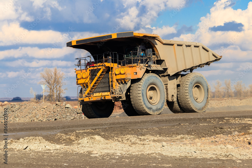 Huge yellow mining dump truck working in iron ore quarry. Mining industry Huge yellow mining dump truck working in iron ore quarry. Mining industry