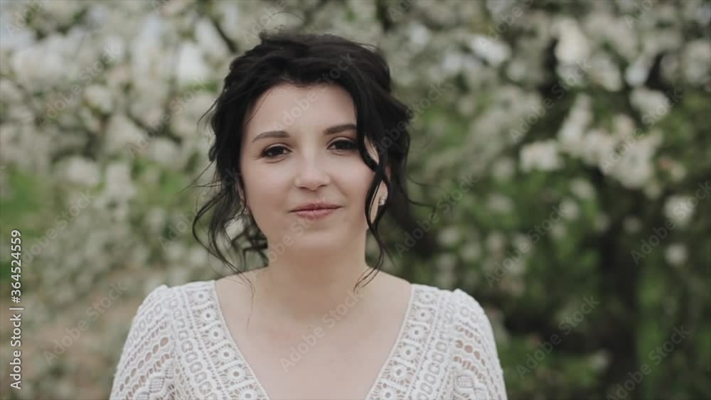 A gentle young girl with a calm smile walks through the blossoming spring garden. Close-up. Slow-motion A gentle young girl with a calm smile walks through the blossoming spring garden. Close-up. Slow-motion