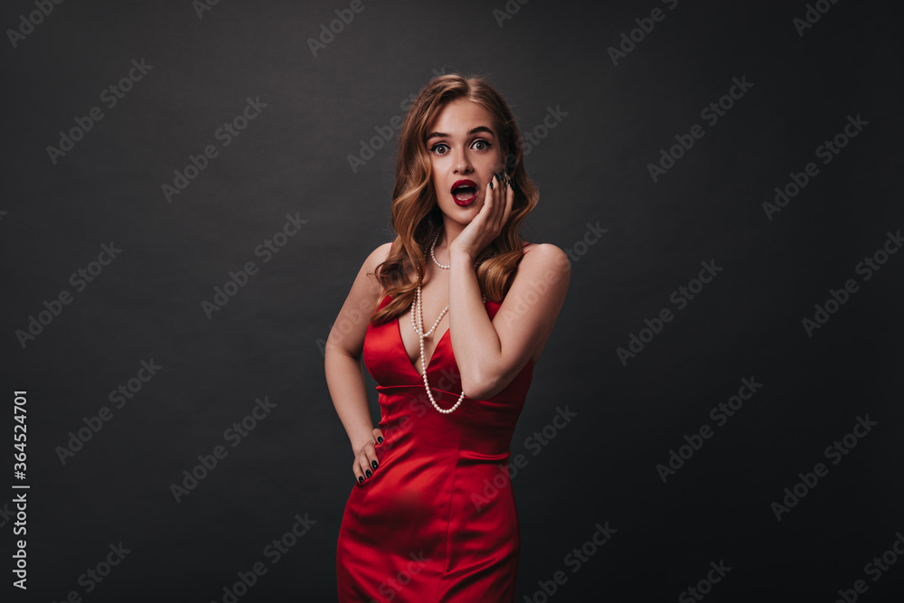 Fototapeta premium Nice woman in red elegant dress surprised looking into camera
