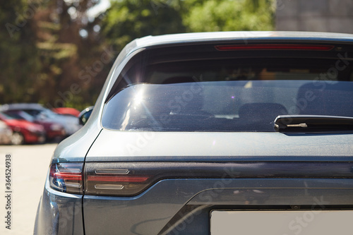 Back window of black car parked on the street in summer sunny day, rear view. Mock-up for sticker or decals