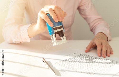 Fotografie Young businesswoman or notary public sitting at the desk in office and stamping