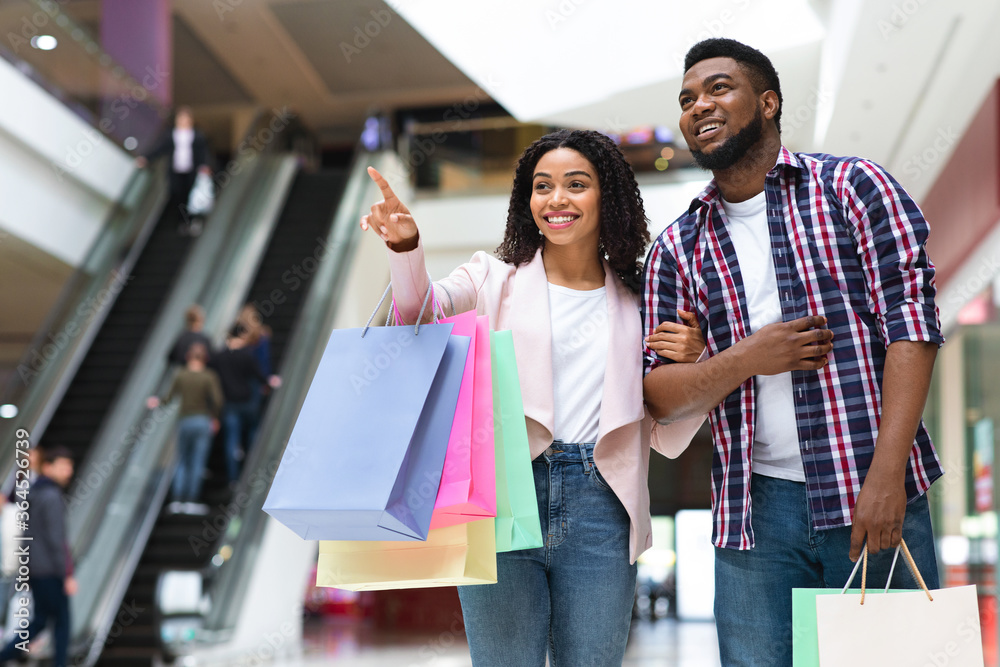 Shopping Together. Black Woman Pointing At Something In Mall, Showing To Boyfriend Shopping Together. Black Woman Pointing At Something In Mall, Showing To Boyfriend