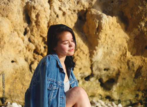 portrait of a woman in a denim jacket on a background of yellow rock