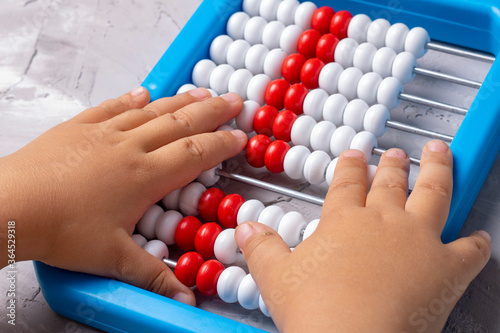 Girl learning with abacus, plays to count. Close up