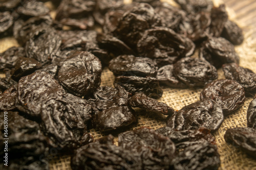 Dried prunes in bulk on burlap with a rough texture. Close up.
