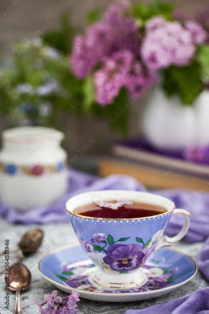 Purple cup of tea and lilac on gray background Purple cup of tea and lilac on gray background