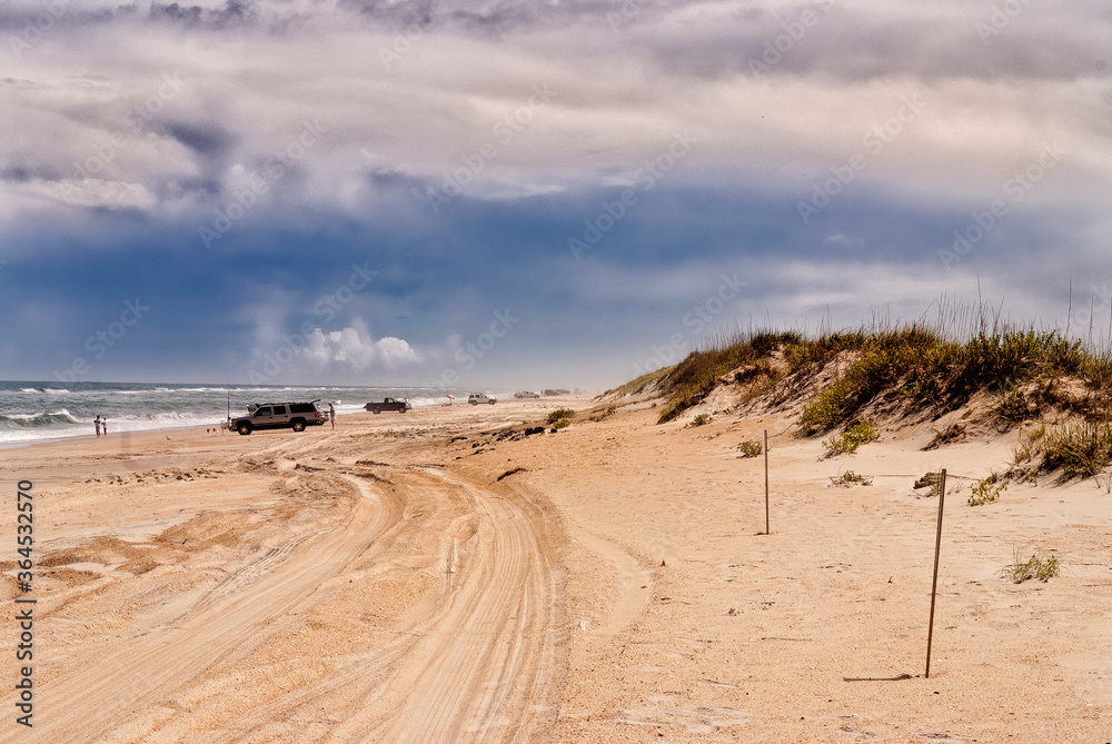 Vehicles parked on the beach leaving tire tracks in the sand at Outer Banks, North Carolina.