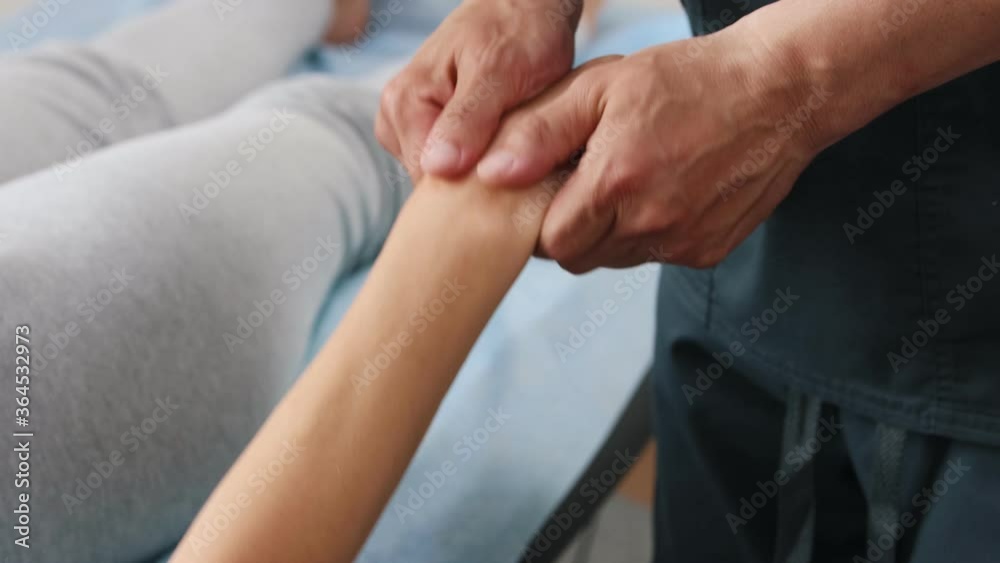 Massagist shaking hand and fingers of young woman Massagist shaking hand and fingers of young woman