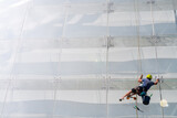 Window washer works on the wall of a glass building.