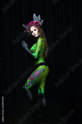 beautiful girl painted with green paint and flowers on her face and burgundy peonies in her body posing in different poses