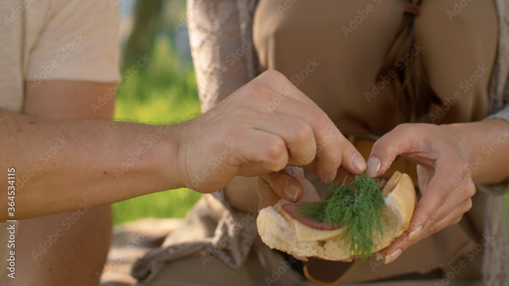 Female and male hands cooking sandwich