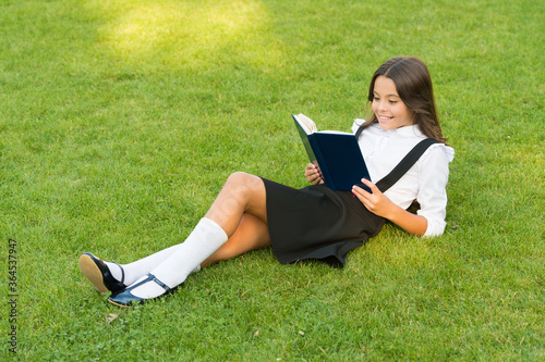 Be educated. study literature for children. having fun with book. knowledge day. modern school education. happy childhood. teen girl with book on green grass. pretty child little girl read book