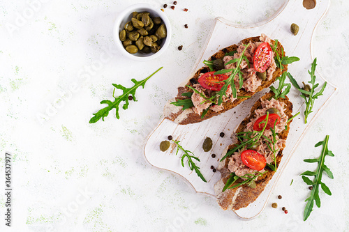 Toasts with tuna. Italian bruschetta sandwiches with canned tuna, tomatoes and capers. Top view, flat lay, copy space