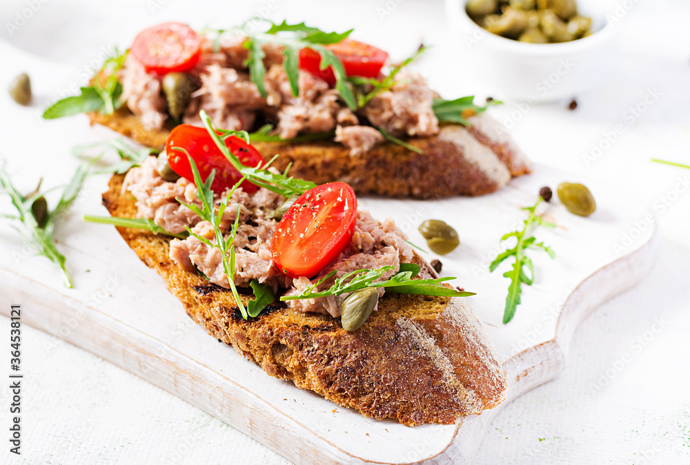 Toasts with tuna. Italian bruschetta sandwiches with canned tuna, tomatoes and capers.