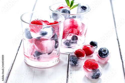 Frozen berries in glass for cocktail on wooden table background
