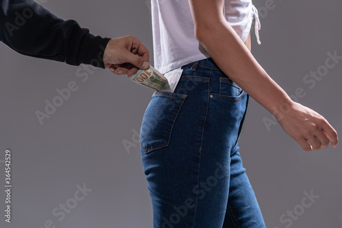 Billede på lærred Thief pickpocket stealing a dollar bill from the back jeans pocket of women's jeans