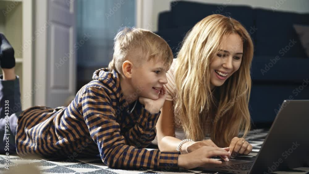A Young woman mother teaches her son and works with him on a laptop at home. Social distancing and self isolation in quarantine lockdown. Home school education and parents teaching kids at home. A Young woman mother teaches her son and works with him on a laptop at home. Social distancing and self isolation in quarantine lockdown. Home school education and parents teaching kids at home.