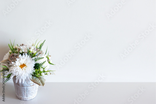 Fototapeta Naklejka Na Ścianę i Meble -  Wall mockup with pot of flowers on white surface. Copy space.