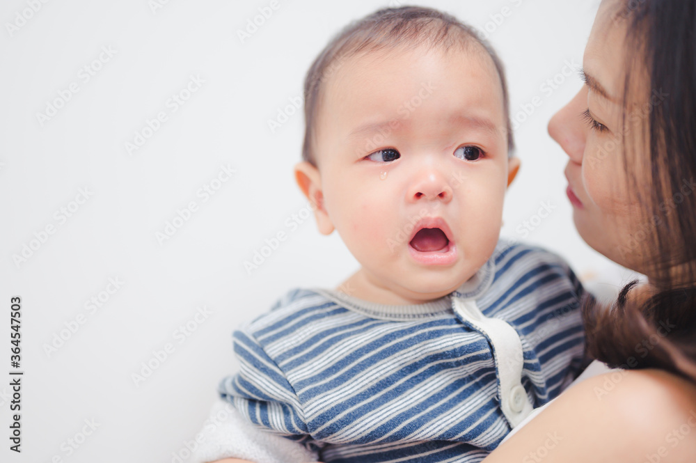 Portrait of 8 months baby boy crying with mother while she holds him and tries to comfort him. Portrait of 8 months baby boy crying with mother while she holds him and tries to comfort him.
