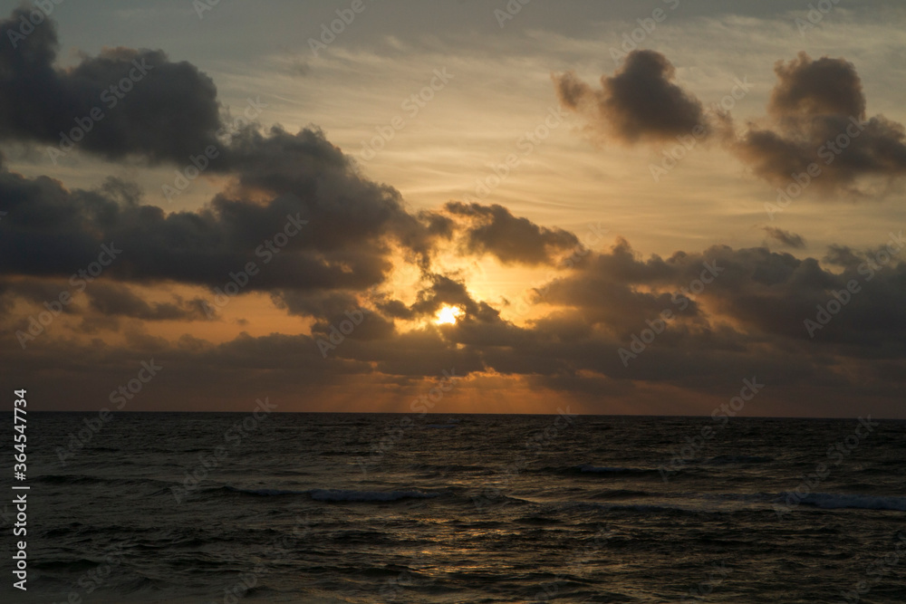 Obraz premium Dramatic sky and clouds. Seascape. The sea and ocean waves at sunrise. Beautiful daybreak orange, yellow and red colors.