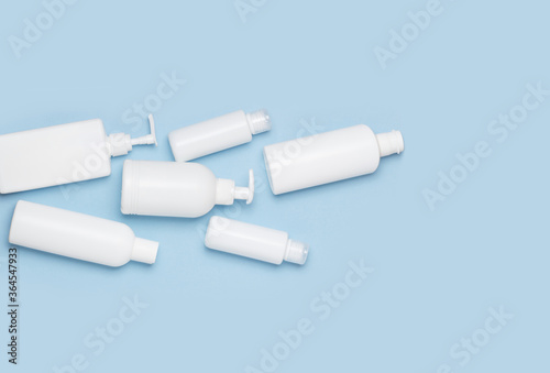 A set of white cosmetic cans for face and body care are in a basket on a blue background. Purchase of cosmetics and hygiene products, home shopping