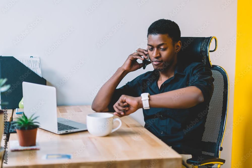 African american young man checking time on smartwatch while calling on ...