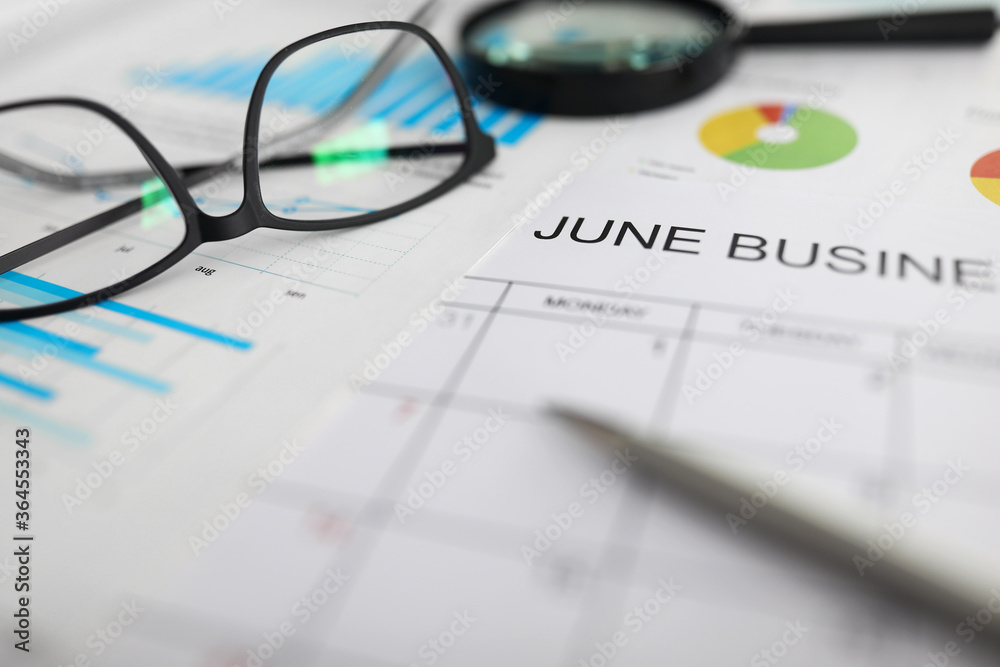 Paper timetable for june lying at workplace among charts Paper timetable for june lying at workplace among charts