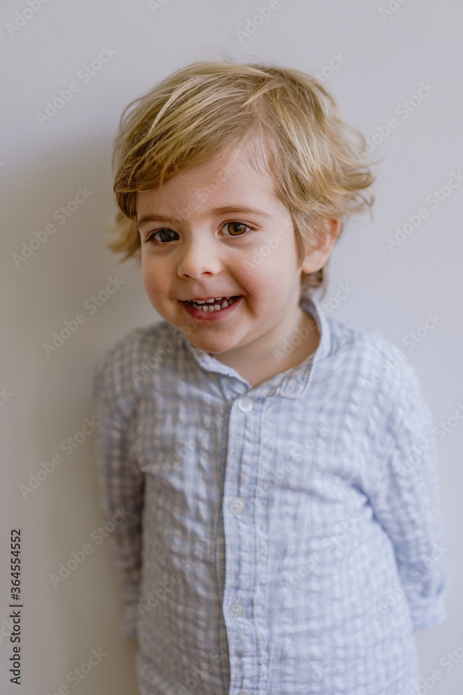 Adorable little kid wearing casual shirt smiling and looking at camera on white background of studio