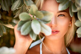 Portrait of a blonde with natural beauty among the leaves of tropical trees. Spa and pleasure