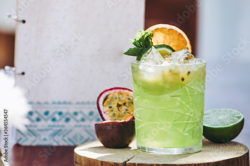 Glass of cold green alcohol Mojito cocktail with fresh passion fruit and lime garnished with mint leaves and fruit slices photo