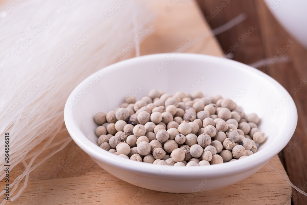 white Pepper seeds in white bowl on chopper board background white Pepper seeds in white bowl on chopper board background