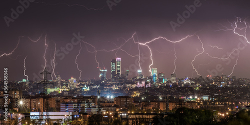 Amazing panoramic view of modern city with contemporary buildings and skyscrapers under dark night sky illuminated by plenty of lightnings photo