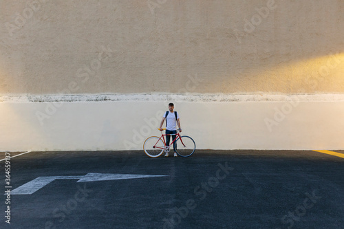 Man with a bike in the middle of a car park at last hour of the day. photo