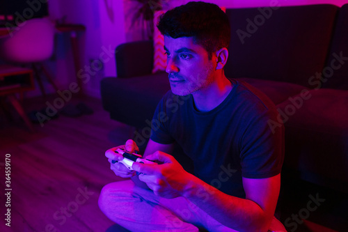 Close-up view of a young caucasian male playing video games with colorful lights photo