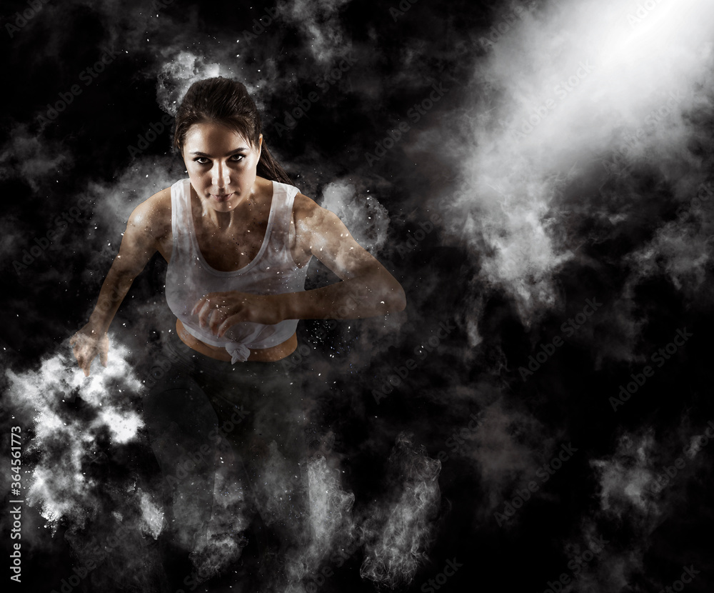Sporty young woman running on smoke background