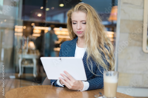 Young businesswoman on a coffee break. Using tablet computer. © Minerva Studio