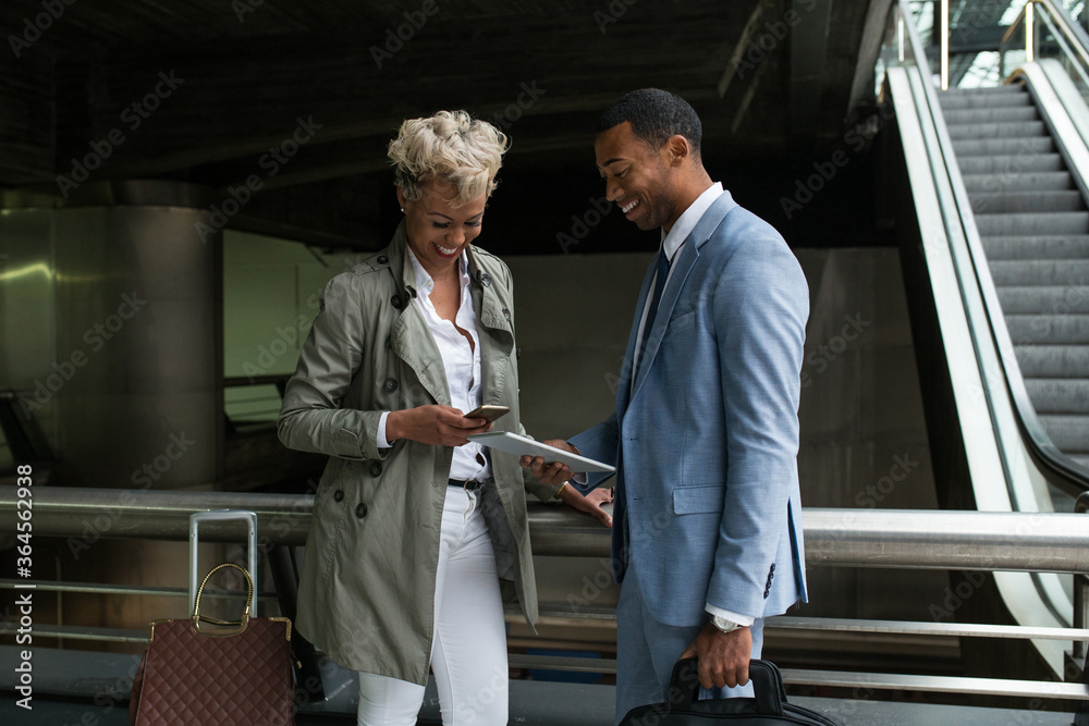 Cheerful elegant African-American man and woman watching tablet together and smiling.